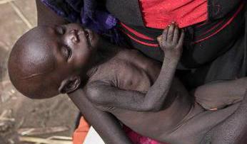 En kvinna i Sydsudan håller sin tio månader gamla dotter i famnen, medan hon väntar på mat från en hjälporganisation.  Foto: STR/AP/TT