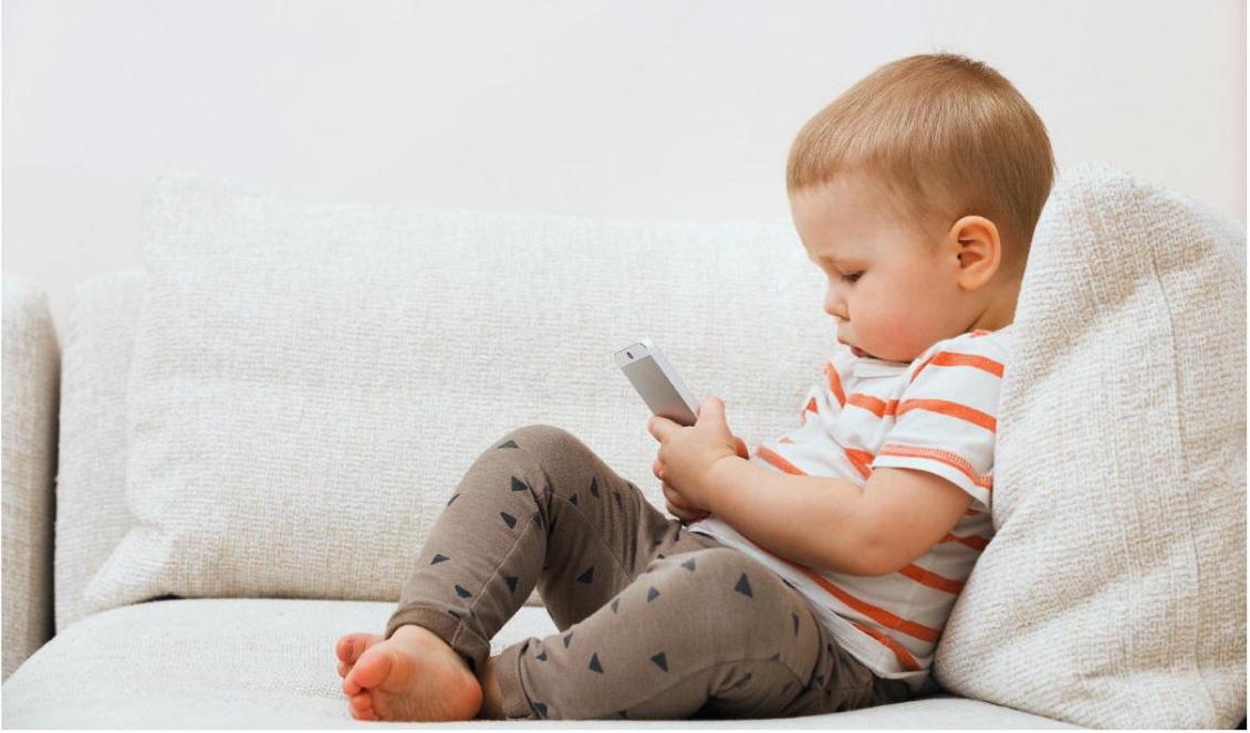 Ett litet barn med en mobiltelefon i sin hand, en vanlig syn i dag. Men måste bebisar verkligen vara insatta i den senaste digitala tekniken? Foto: Shutterstock