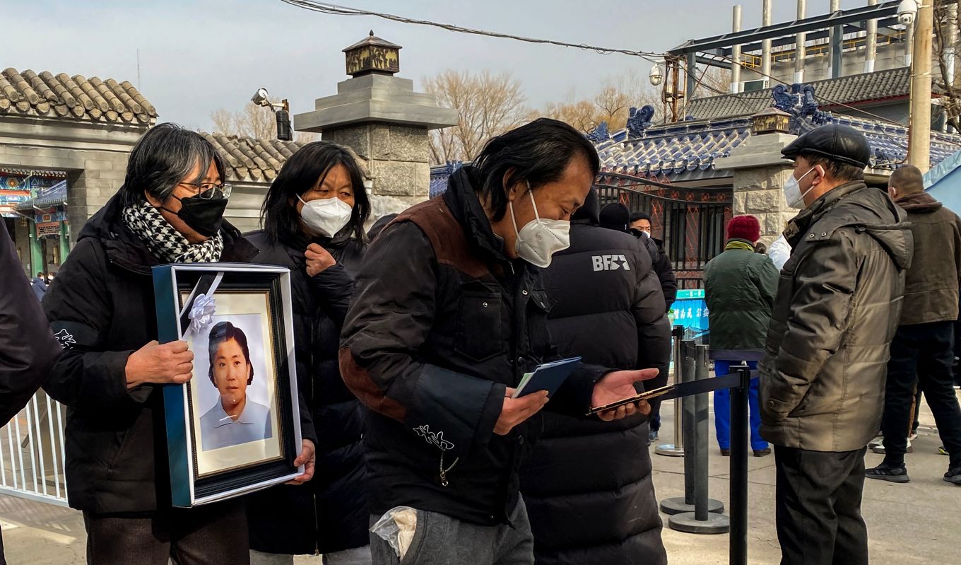 Anhöriga bär en bild på en familjemedlem utanför ett krematorium i Peking i Kina den 20 december 2022. Foto: Noel Celis/AFP via Getty Images