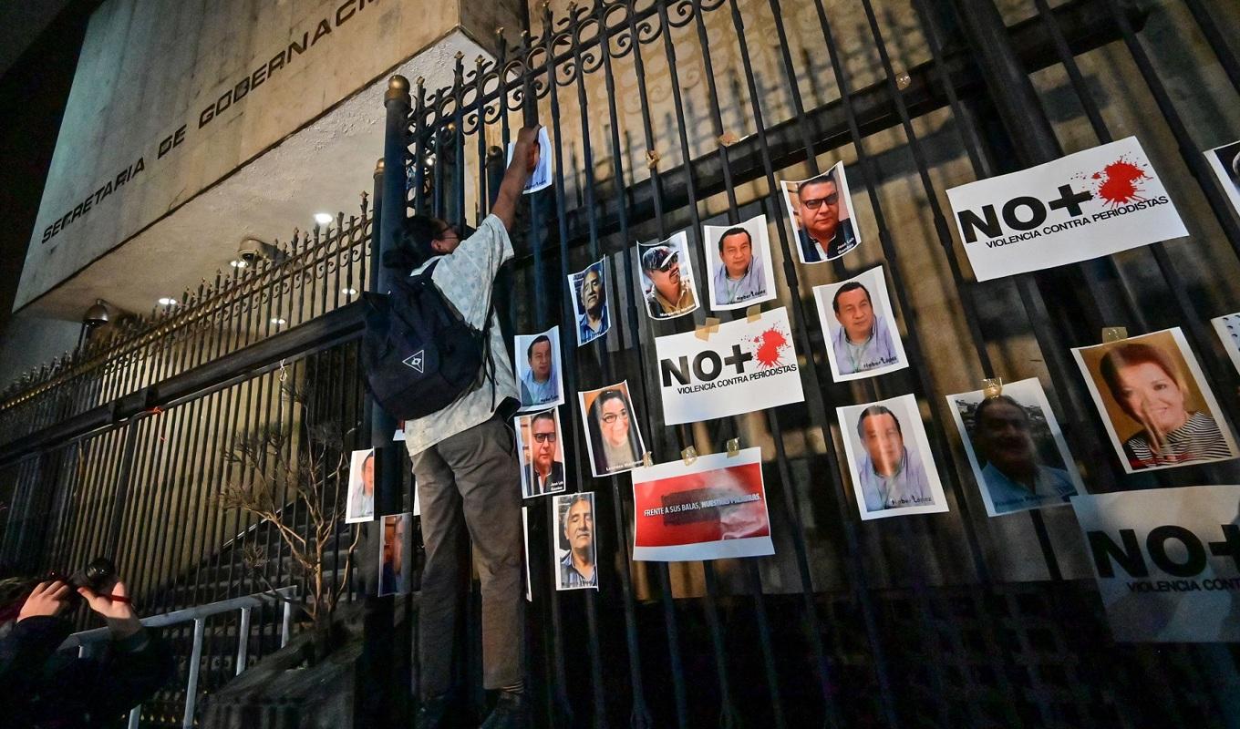 
En journalist hänger upp foton av mördade journalister 2022 under en demonstration vid inrikesdepartementet i Mexico City i Mexiko den 14 februari 2022. Foto: Pedro Pardo/AFP via Getty Images                                            