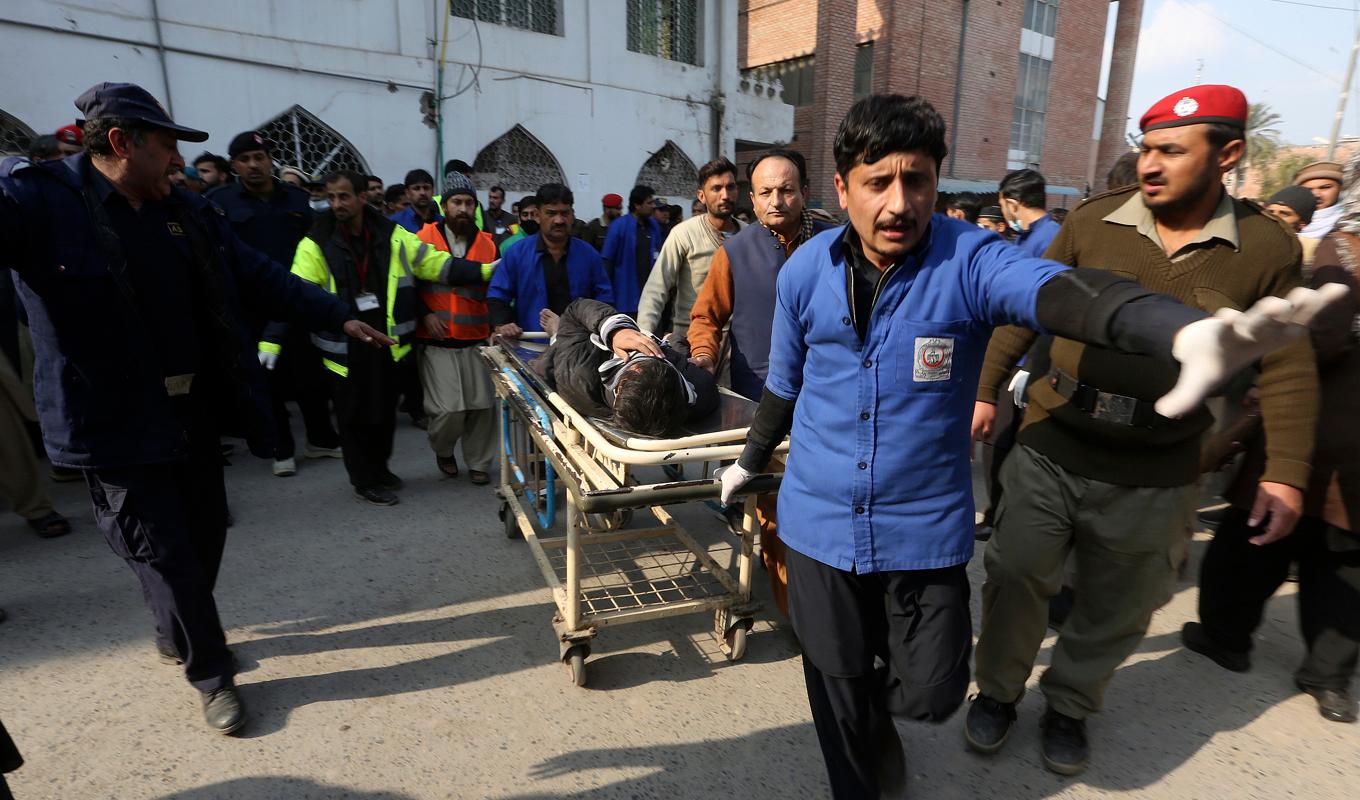En skadad man förs bort från moskén efter explosionen. Foto: Muhammad Sajjad/AP/TT