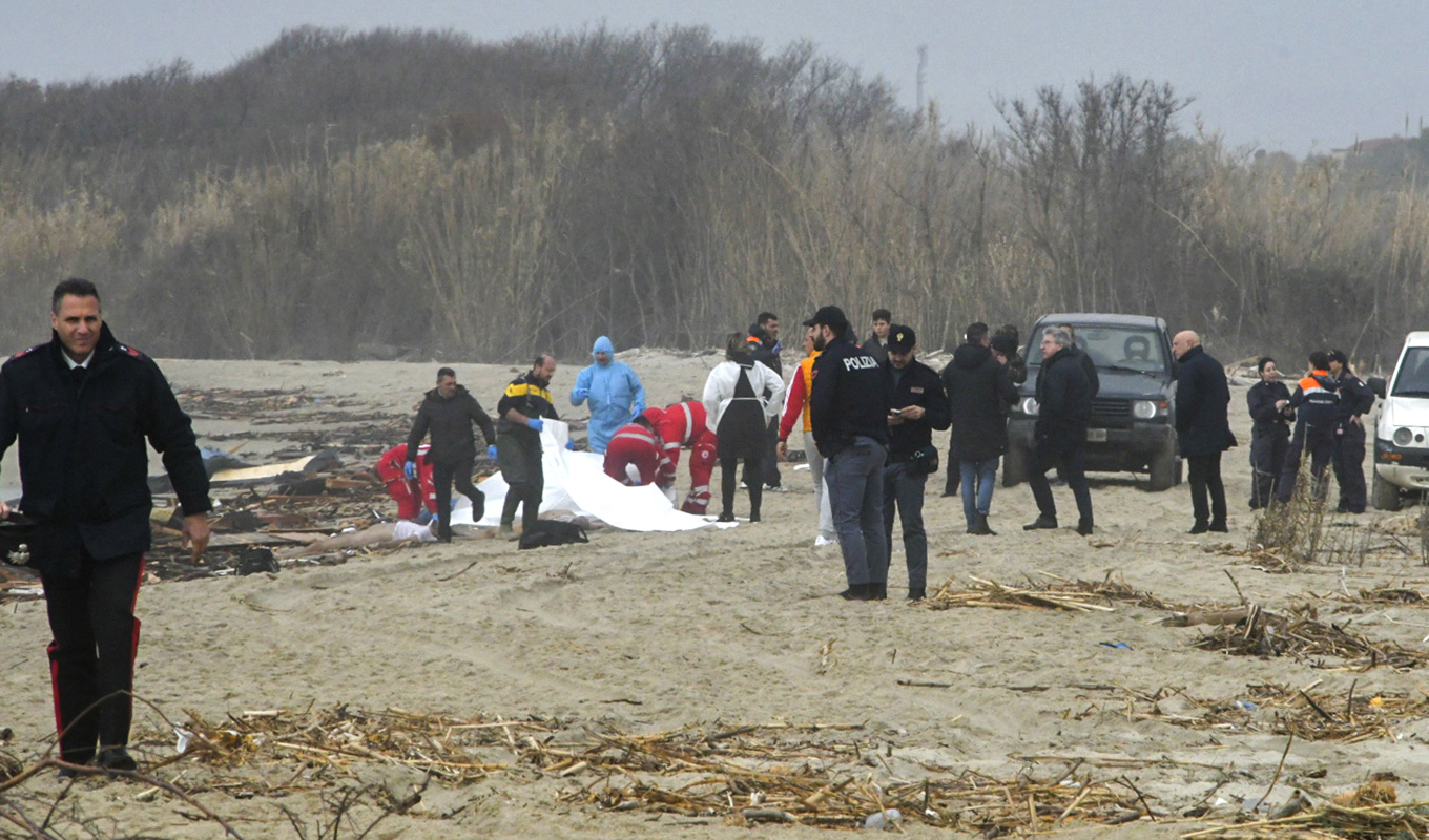 Räddningsarbetare i södra Italien tar hand om en av dem som omkommit sedan en båt med migranter kapsejsat i havet utanför. Foto: Giuseppe Pipita/AP/TT