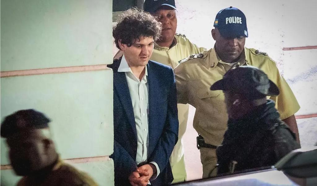 Grundaren av den havererade kryptobörsen FTX, Sam Bankman-Fried, leds bort av polis i Bahamas efter att ha gripits den 13 december. Foto: Mario Duncanson/AFP via Getty Images