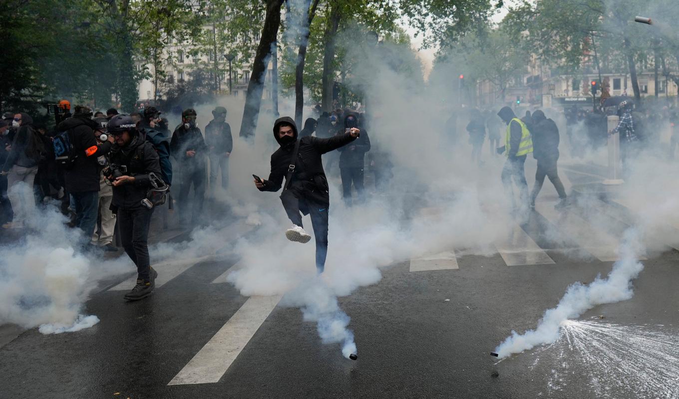 Unga demonstranter sparkar tillbaka polisens tårgaspatroner vid en demonstration i Paris. Foto: Thibault Camus/AP/TT