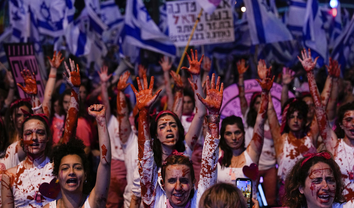 Israeliska aktivister i Tel Aviv som stänkt sig själv i röd färg för att öka kännedomen kring våld mot kvinnor under protesterna mot Netanyahus planerade lagändringar. Foto: Ariel Schalit/AP/TT