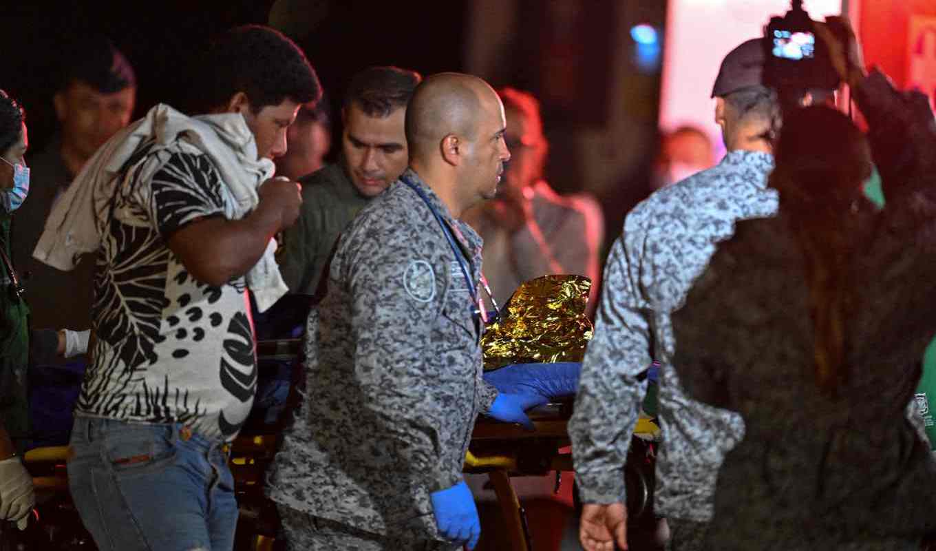 Pappan, i vit tröja till vänster, går med ett av sina barn som förs till militärsjukhuset i Bogotá. Bild från lördagen. Foto: Juan Barreto/AFP/TT