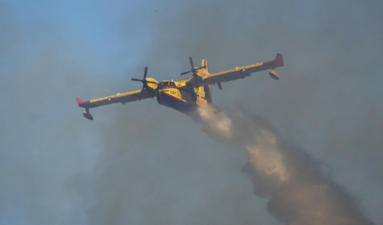Ett vattenbombande flygplan bekämpar bränder över Rhodos under tisdagen. Planet på bilden är inte det som har störtat. Foto: Petros Giannakouris/AP/TT