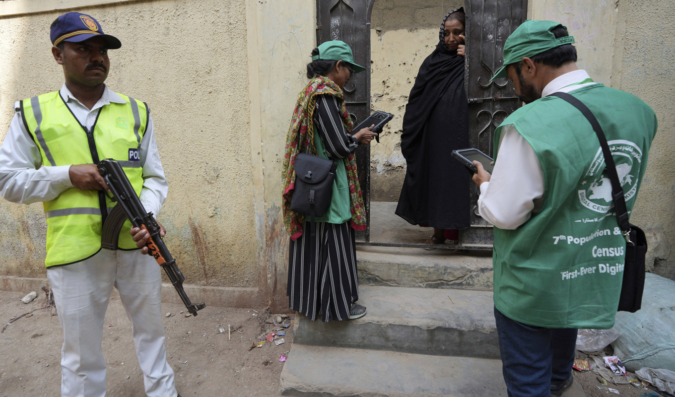 En polis håller vakt medan en utsänd från statistikmyndigheten samlar uppgifter från en kvinna under folkräkningen i Peshawar i Pakistan i år. Foto: Fareed Khan/AP/TT