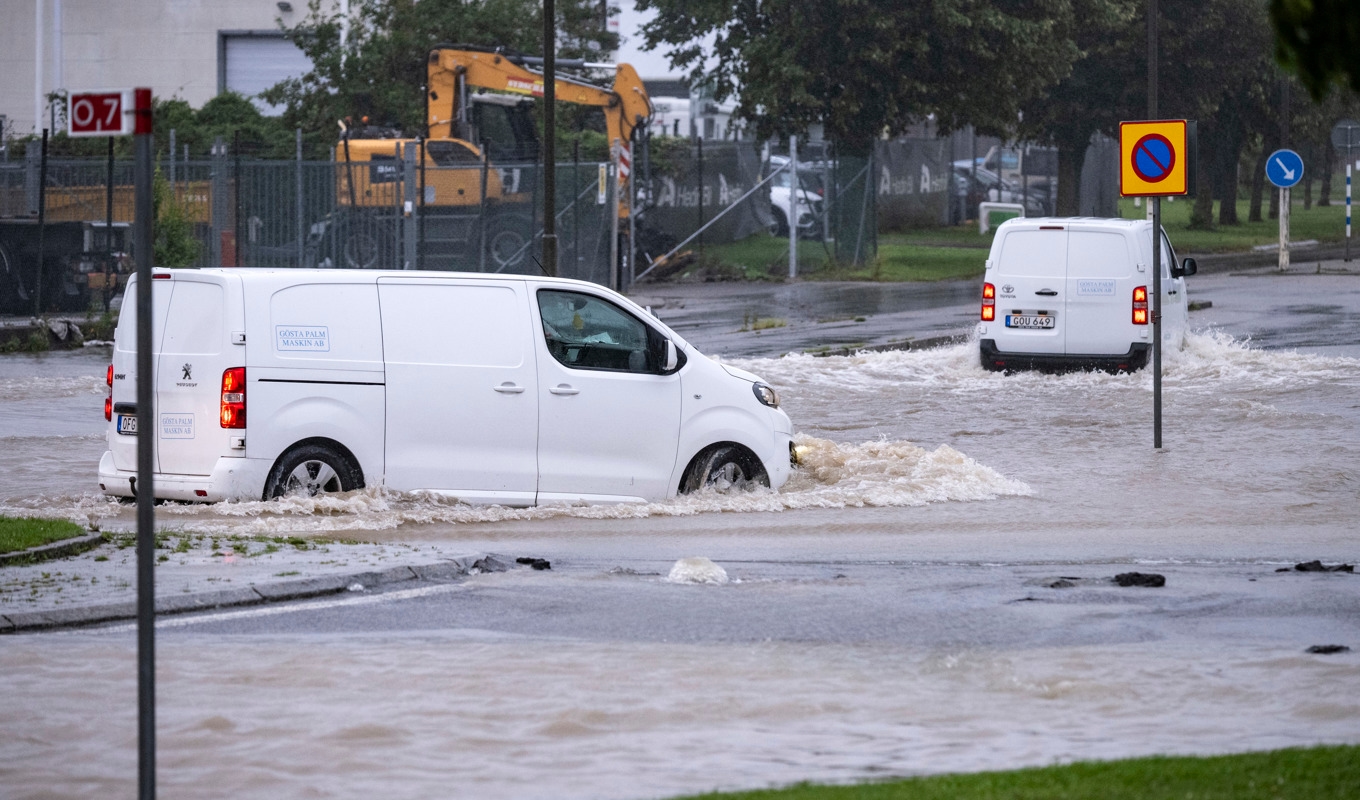 Bilar försöker ta sig genom en översvämmad rondell i Arlöv vid den avstängda, översvämmade Västkustvägen E6 utanför Malmö. Foto: Johan Nilsson/TT