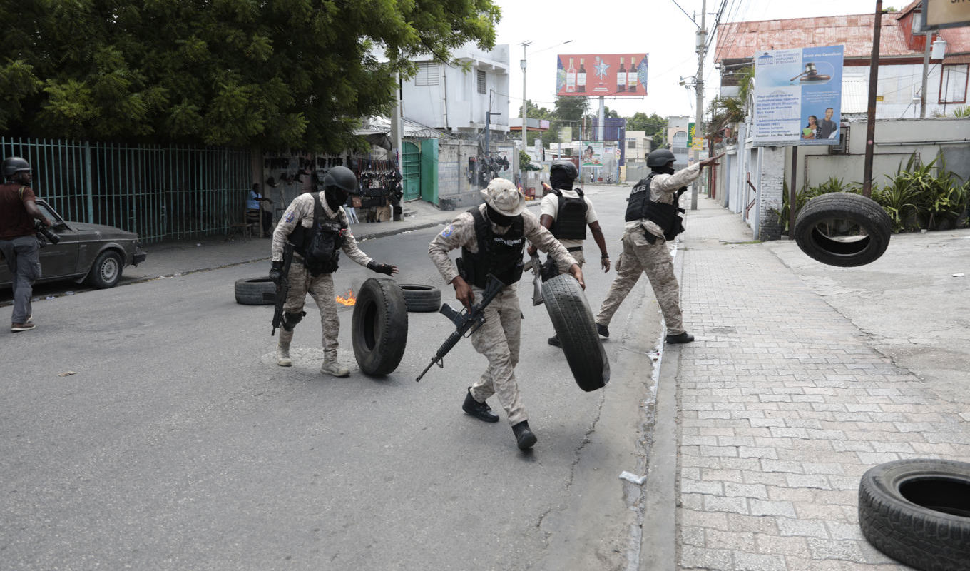 Poliser bär bort däck efter en demonstration i Haitis huvudstad Port-au-Prince mot bristen på säkerhet. Bilden är tagen 14 augusti. Foto: Odelyn Joseph/AP/TT