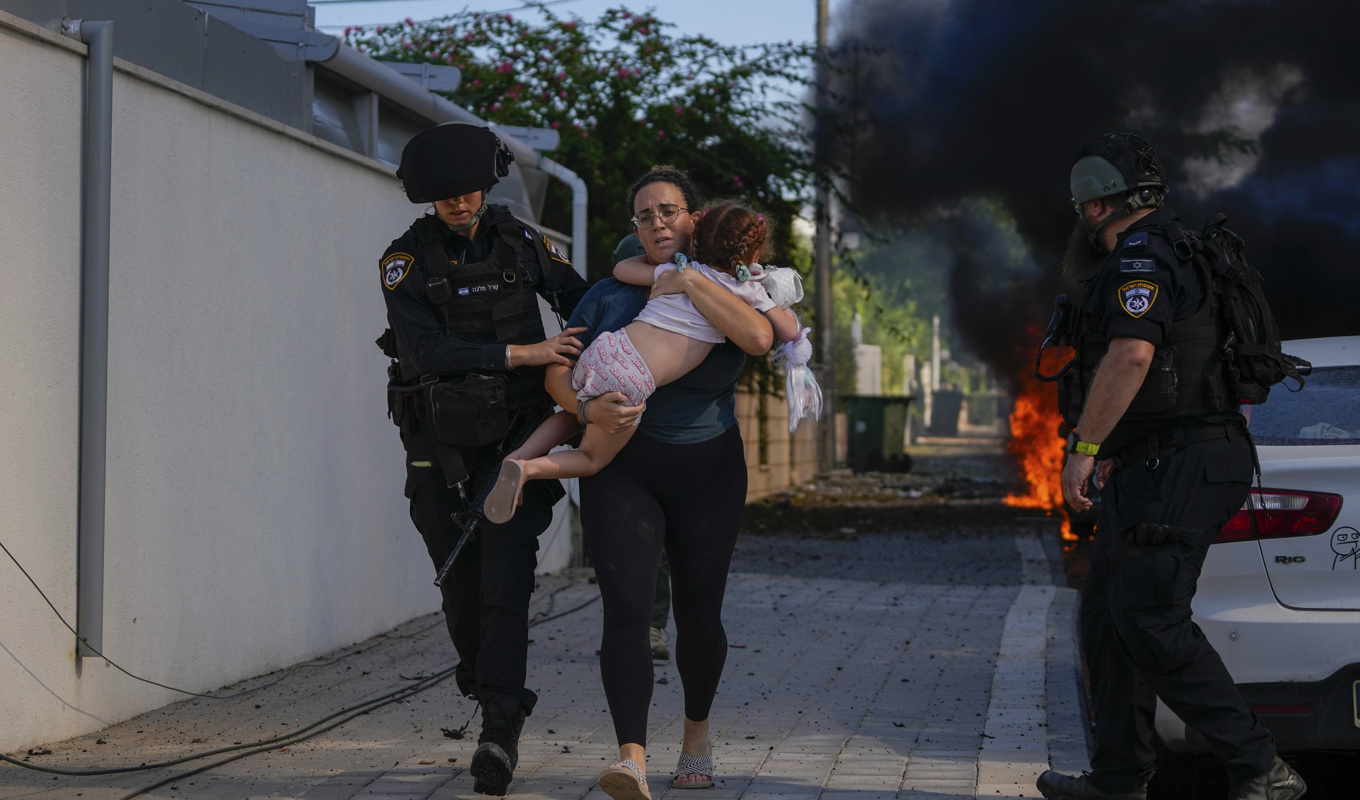 Israelisk polis hjälper en kvinna och ett barn från ett område som träffats av en raket i Ashkelon. Foto: Tsafrir Abayov/AP/TT