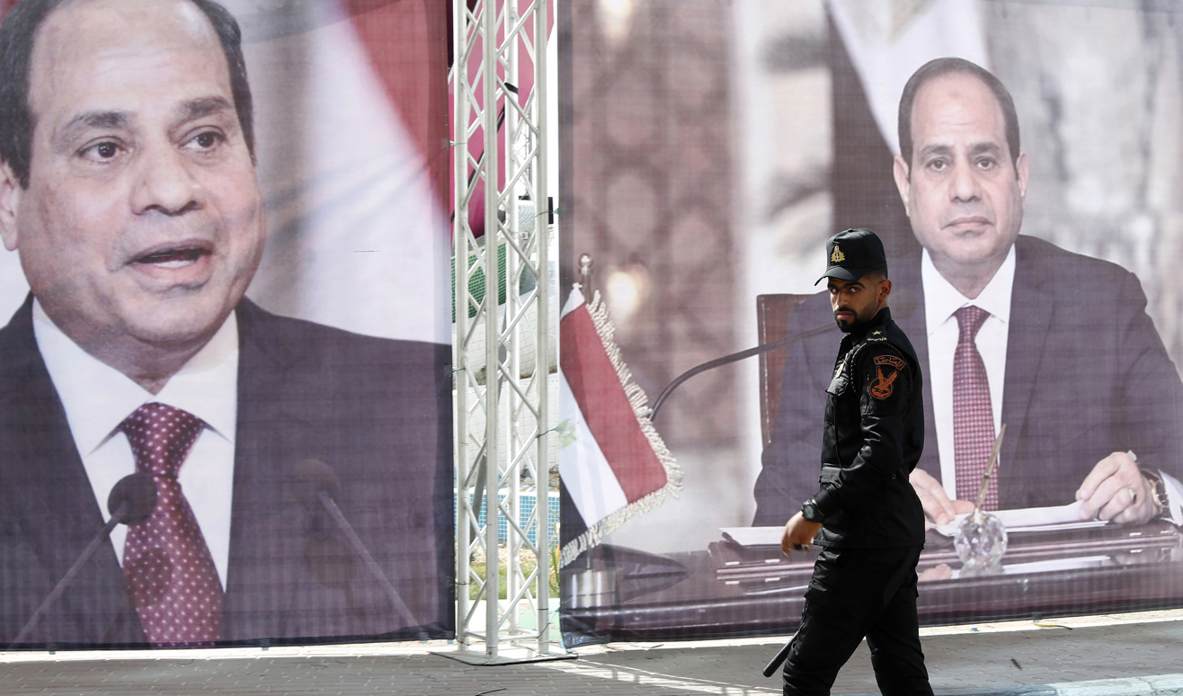 En polis från Hamas patrullerar framför ett porträtt på Egyptens president Abd al-Fattah al-Sisi i maj 2021, i samband med att Egyptens underrättelsechef besökte Gaza. Foto: Adel Hana/AP/TT