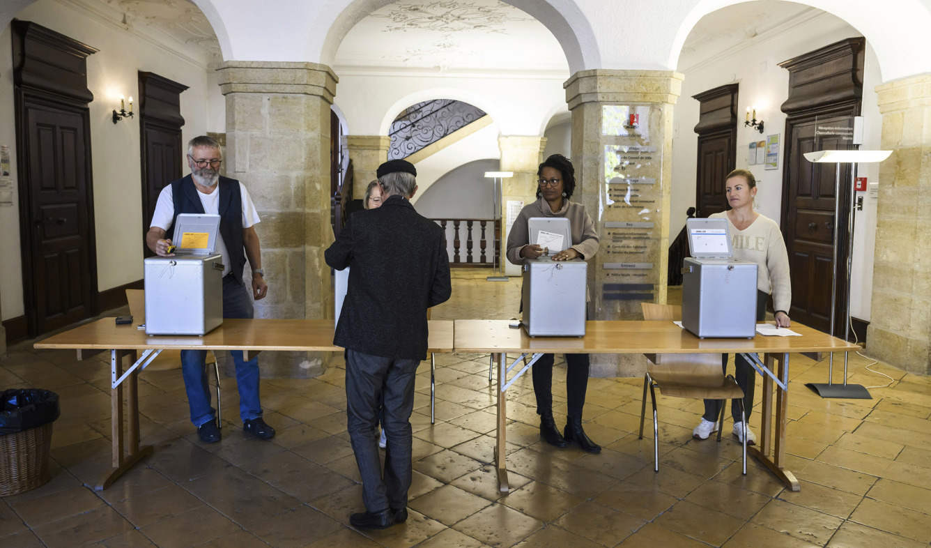 En man röstar under söndagens val i Schweiz. Foto: Jean-christophe Bott/AP/TT