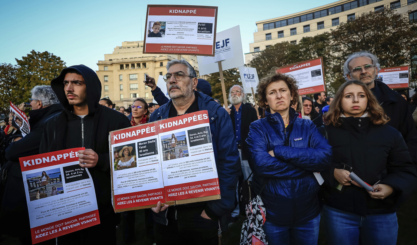 Demonstranter i Paris visar bilder på släktingar som hålls som gisslan av Hamas. Foto: Aurelien Morissard/AP/TT