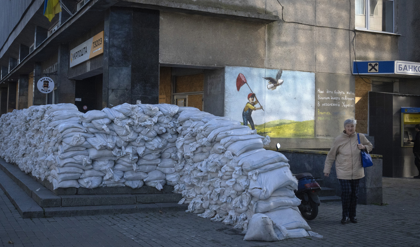 En invånare i staden Cherson promenerar förbi en mur av sandsäckar som byggts för att skydda ett postkontor. Bilden togs den 10 november. Foto: Efrem Lukatsky/AP/TT