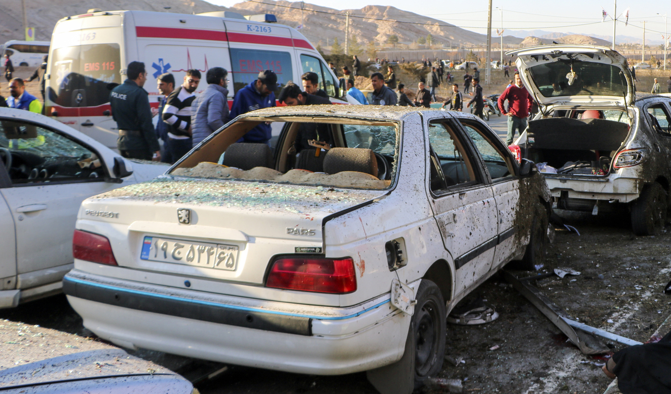 Människor samlade utanför en bil som förstörts i en gårdagens explosioner. Foto: Tasnim News Agency/AP/TT