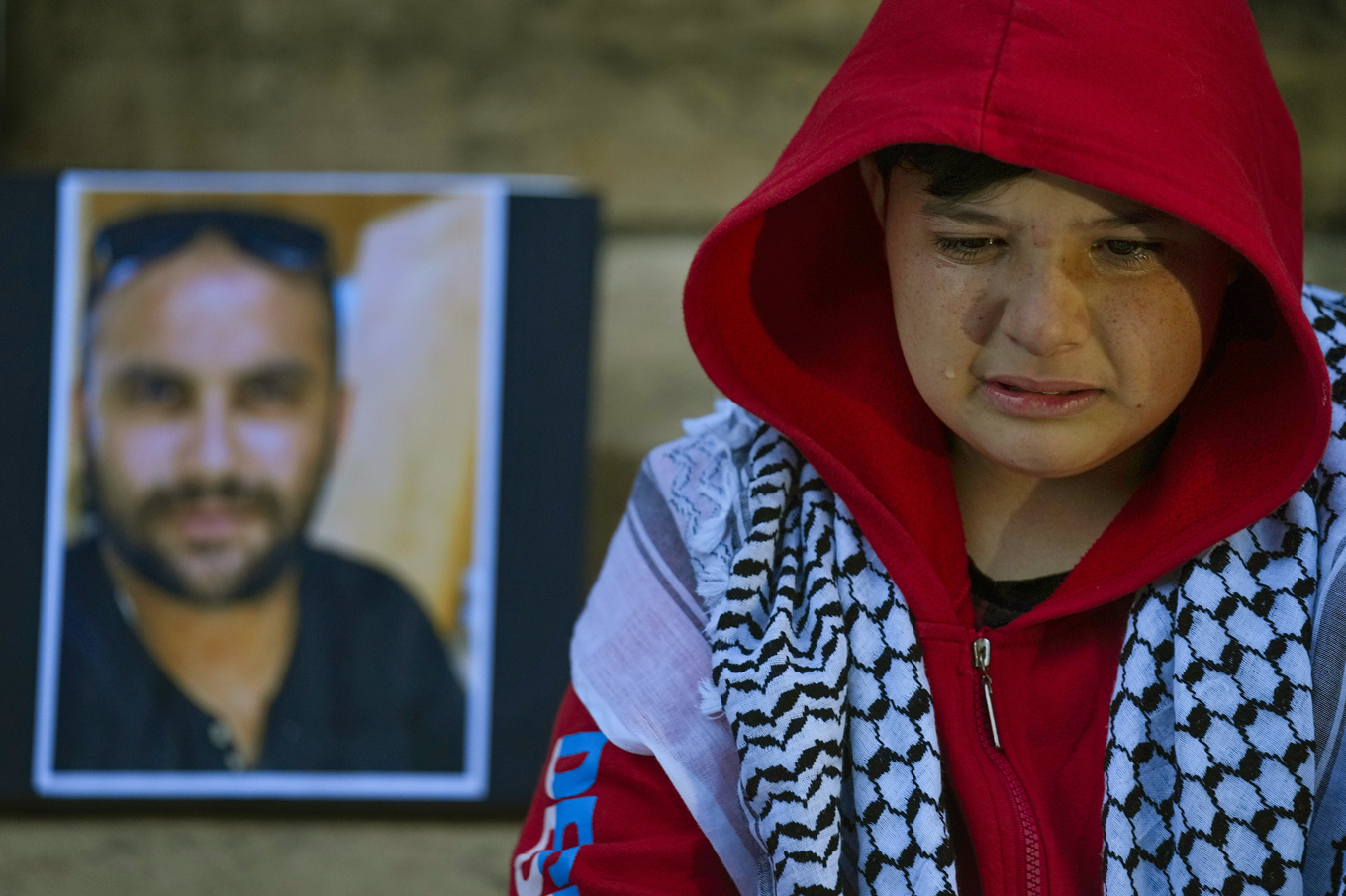 En pojke gråter intill ett porträtt på videojournalisten Issam Abdallah som dödades den 13 oktober. Foto: Bilal Hussein/AP/TT