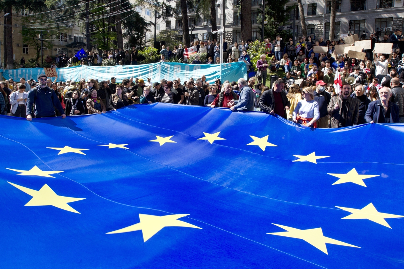 Demonstranter har vecklat upp en stor EU-flagga utanför parlamentsbyggnaden i Tbilisi på måndagen. Foto: Shakh Aivazov/AP/TT