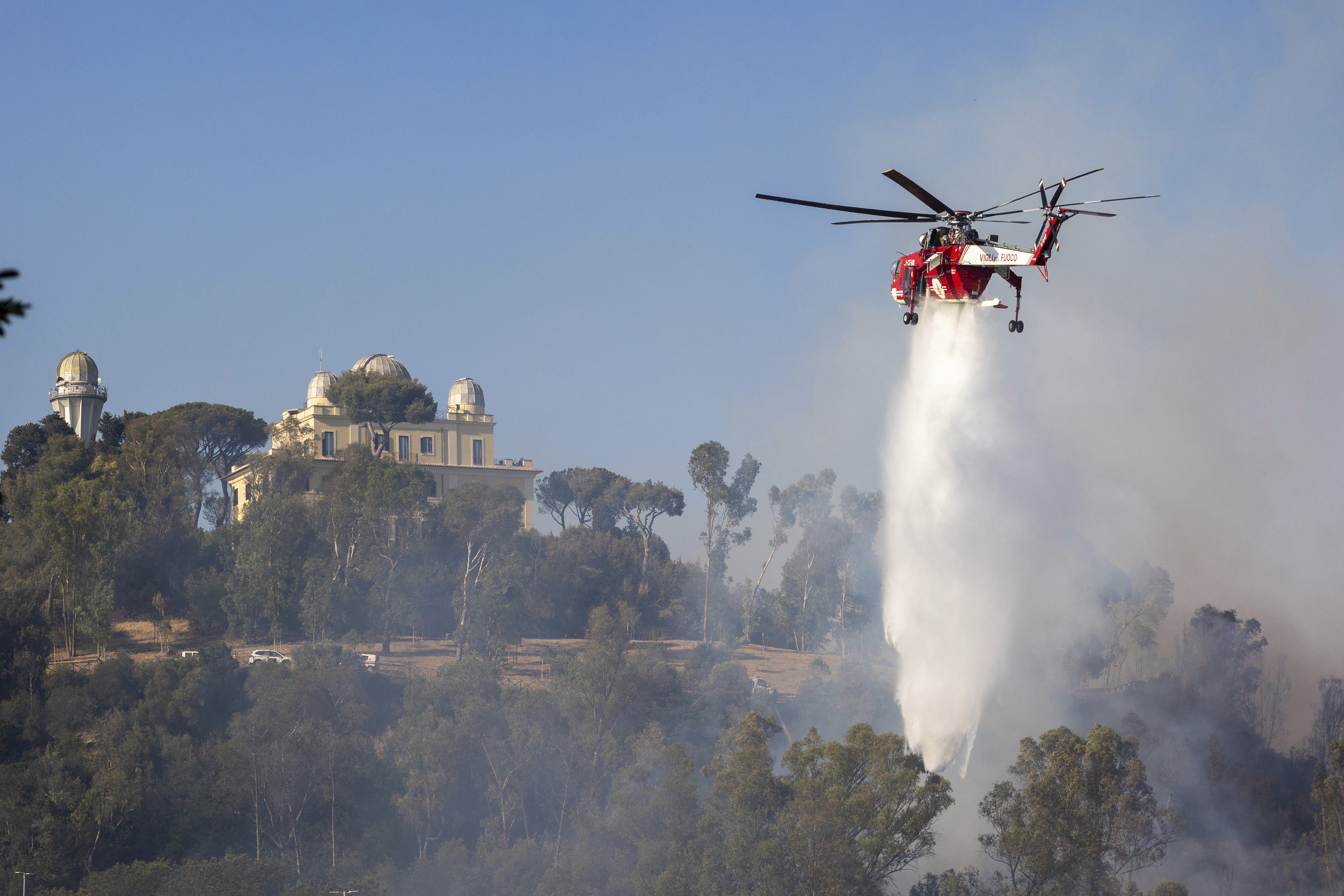 En helikopter vattenbombar branden på Monte Mario i Rom. Foto: Francesco Benvenuti/AP/TT