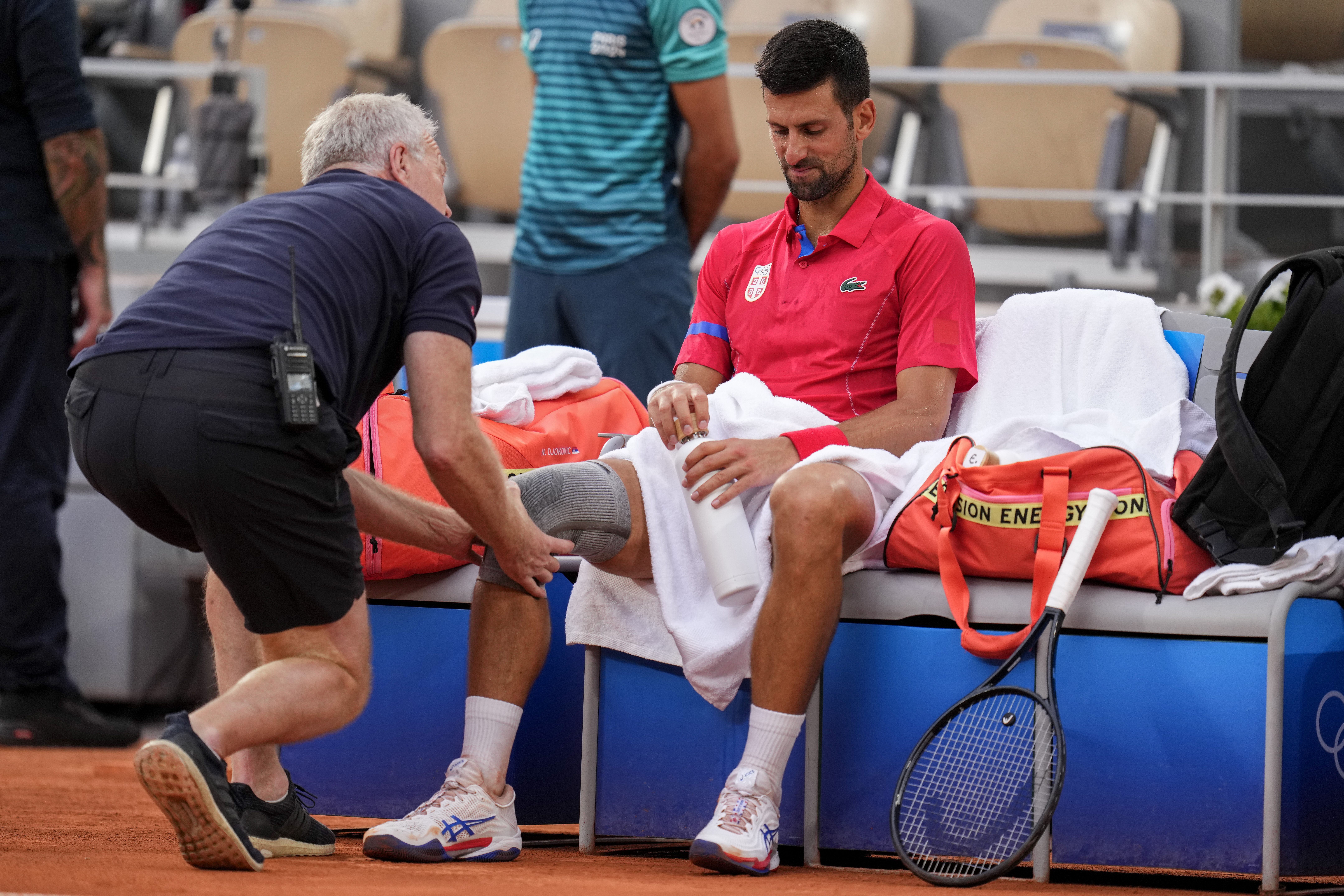 Novak Djokovic får läkarvård för en knäskada under matchen mot Stefanos Tsitsipas på torsdagen. Foto: Manu Fernandez/AP/TT