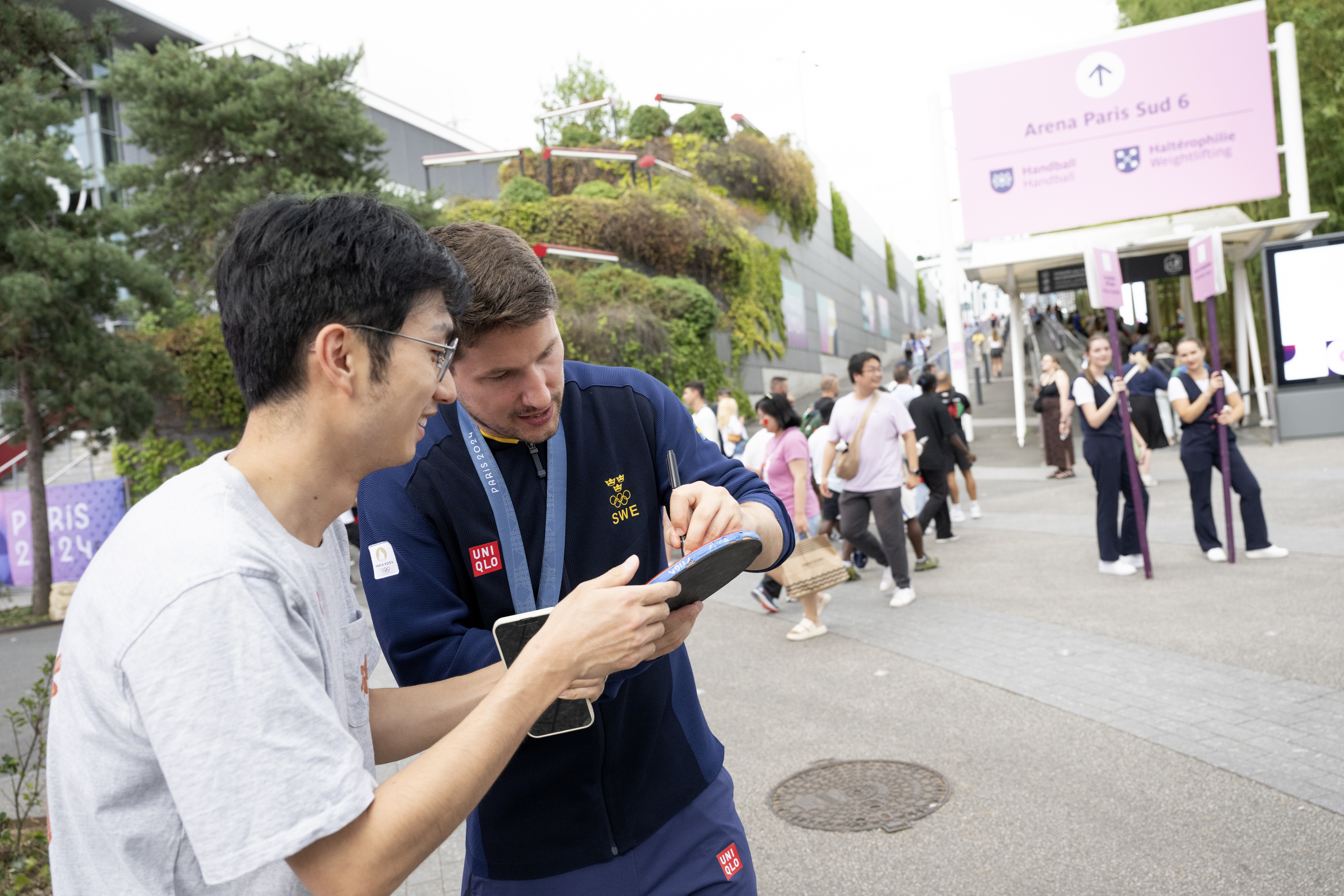 Kristian Karlsson skriver en autograf på ett bordtennisracket i Paris. Foto: Henrik Montgomery/TT