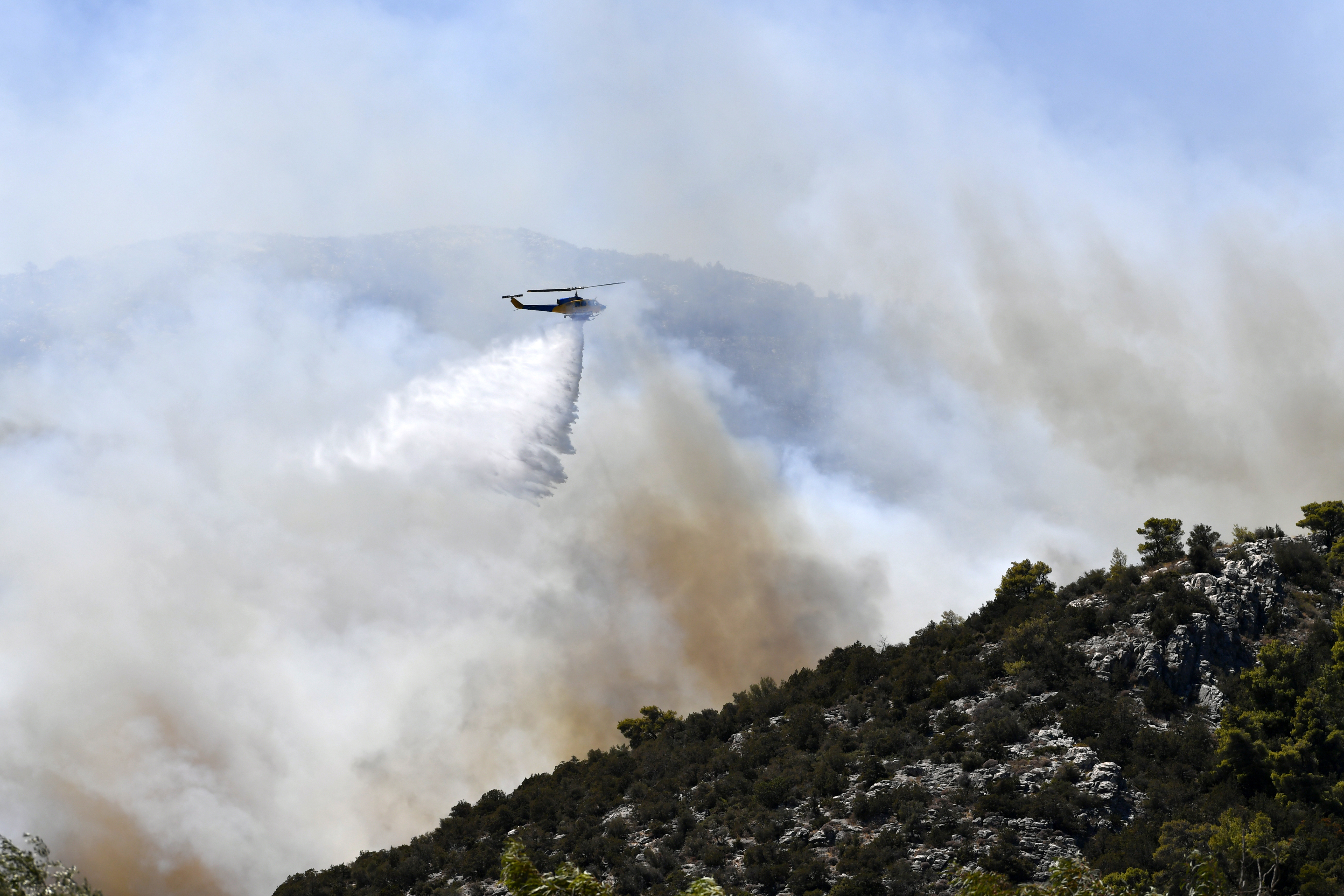 En helikopter bekämpar skogsbranden i Nea Makri, öster om Aten, under måndagen. Foto: Michael Varaklas/AP/TT