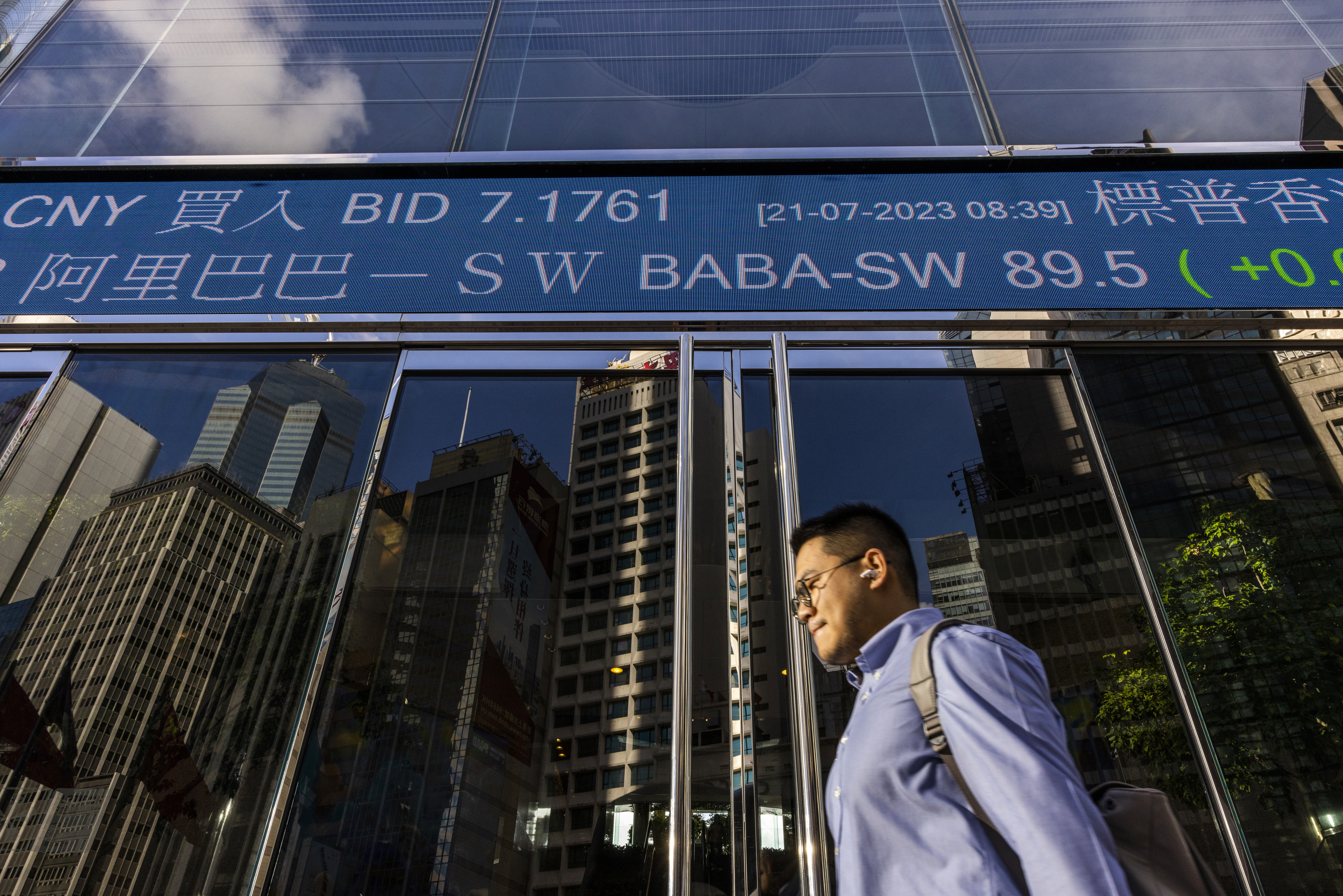 En man passerar skärmen med data för Hongkong-börsen. Arkivbild. Foto: Louise Delmotte/AP/TT