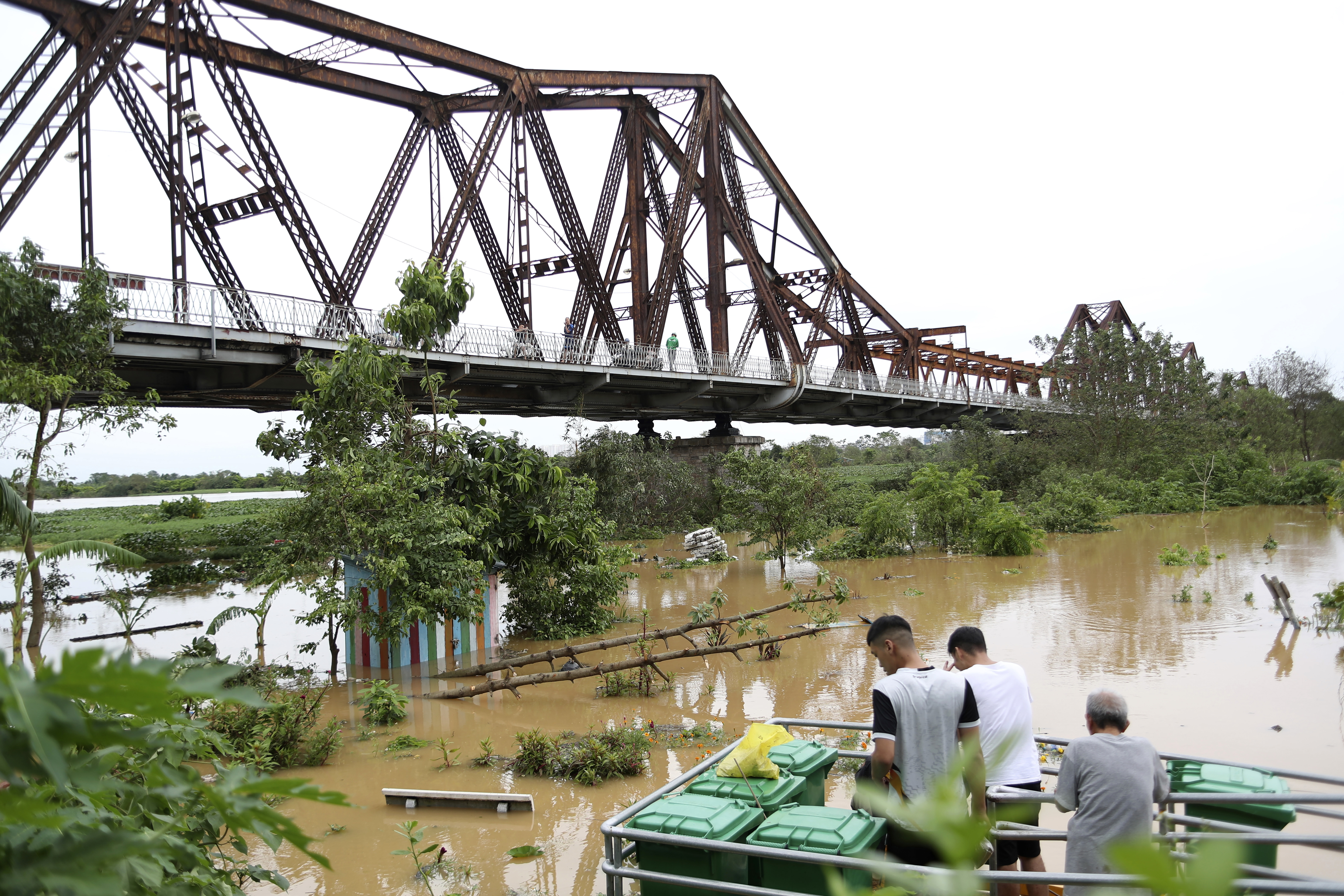 Människor tittar på den översvämmade Röda floden bredvid Long Bien-bron i Hanoi efter tyfonen Yagi. Foto: Huy Han/AP/TT