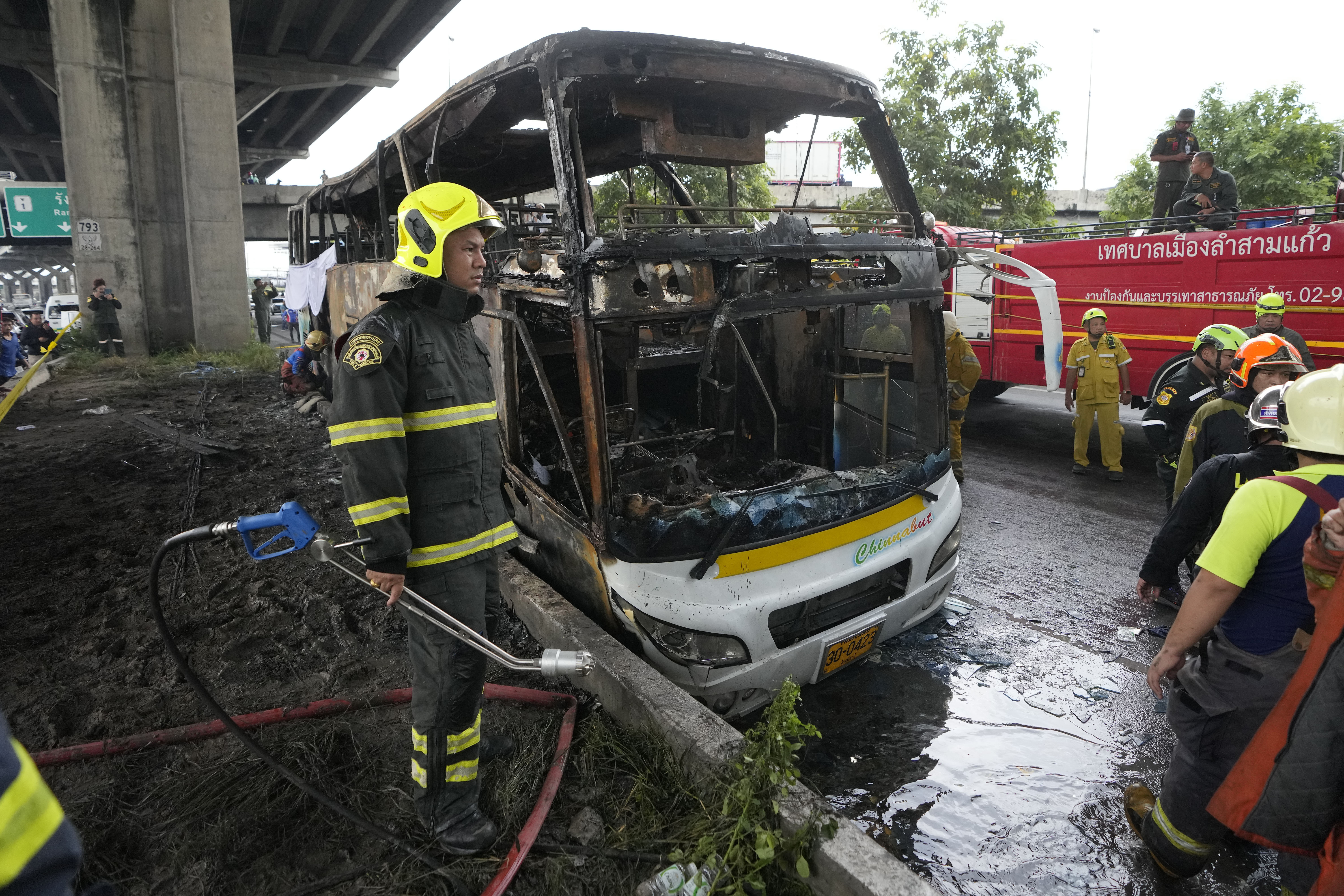 Räddningsinsatser vid bussen som fattade eld i en förort till Bangkok på tisdagen. Foto: Sakchai Lalit/AP/TT