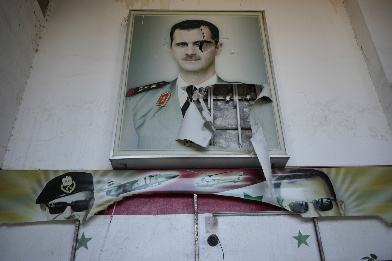 En halvt nedriven affisch på Syriens tidigare president Bashar al-Assad vid ett av Damaskus ökända fängelser. Bild tagen i lördags. Foto: Hussein Malla/AP/TT