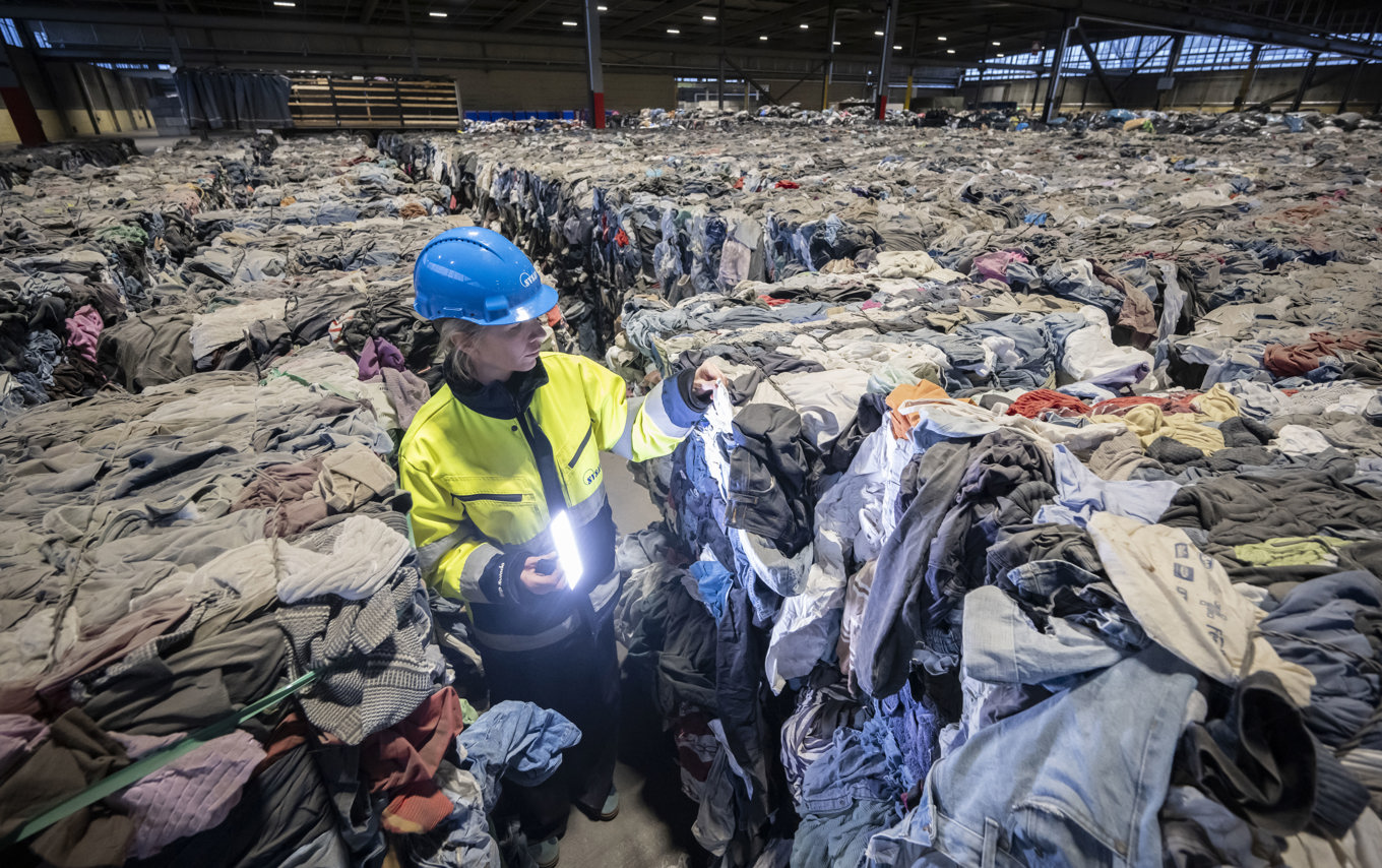 Anna Vilén, kommunikationschef på Sysav, bland långa rader med avlagda kläder som finsorterats av anläggningen Siptex i Malmö. Foto: Johan Nilsson / TT