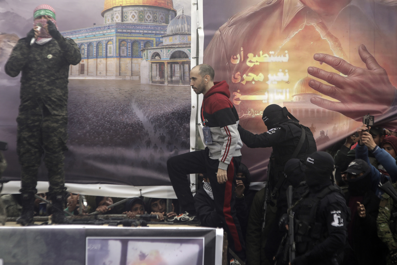 Israelen Tal Shoham eskorteras av Hamas upp på scen innan han lämnas över till Röda korset i Rafaah. Foto: Jehad Alshrafi/AP/TT