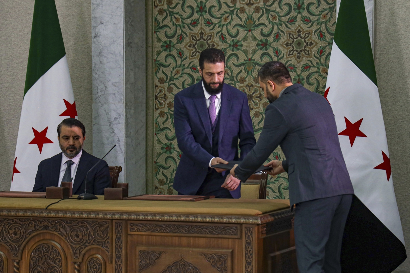 Interimspresident Ahmed al-Sharaa, fotograferad när han i förra veckan skrev under ett provisoriskt grundlagsdokument i Damaskus. Till vänster i bild ses landets interimsutrikesminister Asaad al-Shaibani. Foto: Omar Albam/AP/TT