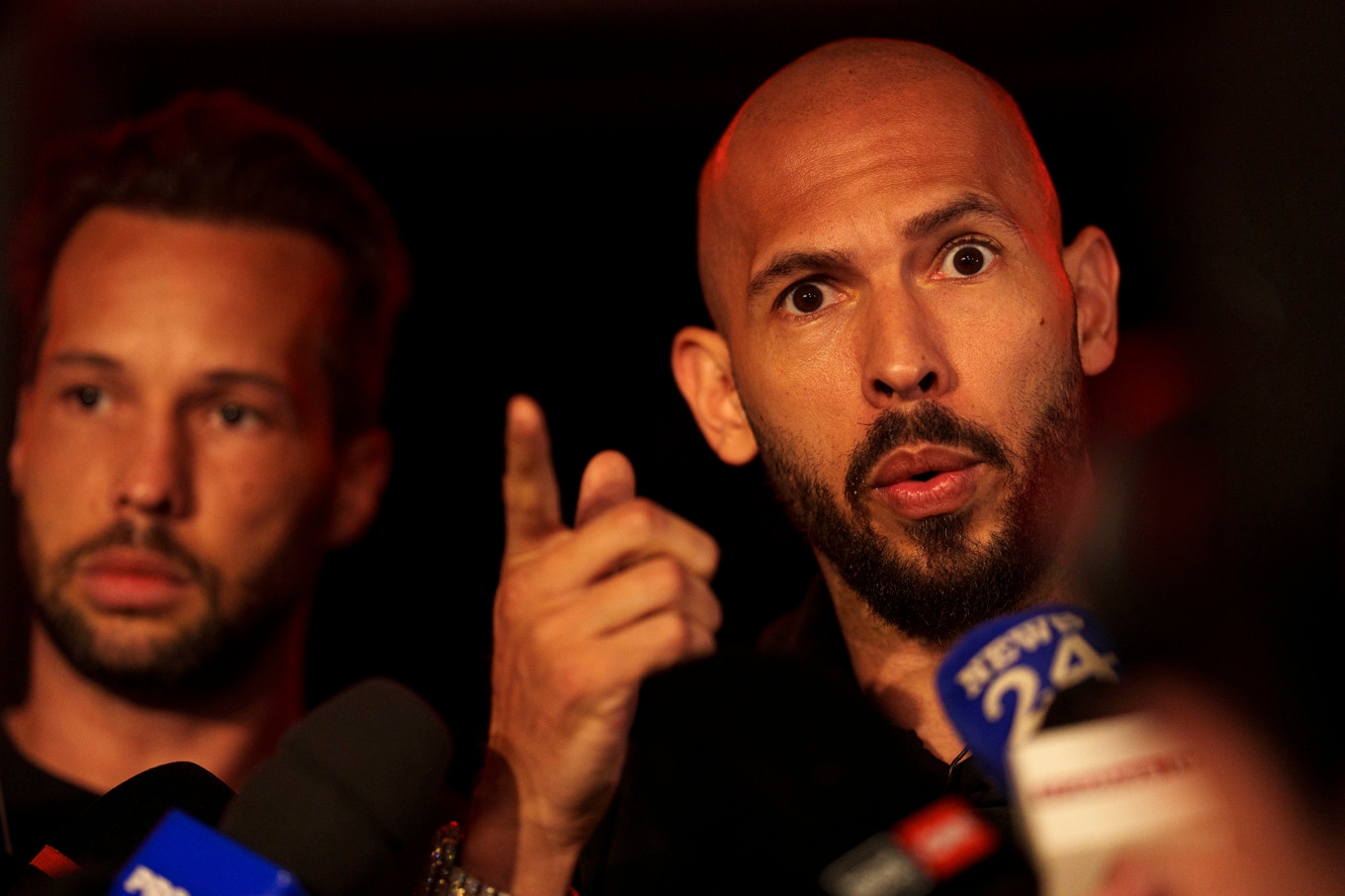 Andrew Tate, höger, pratar med pressen efter att ha återvänt till Rumänien med sin bror Tristan, till vänster. Foto: Vadim Ghirda/AP/TT