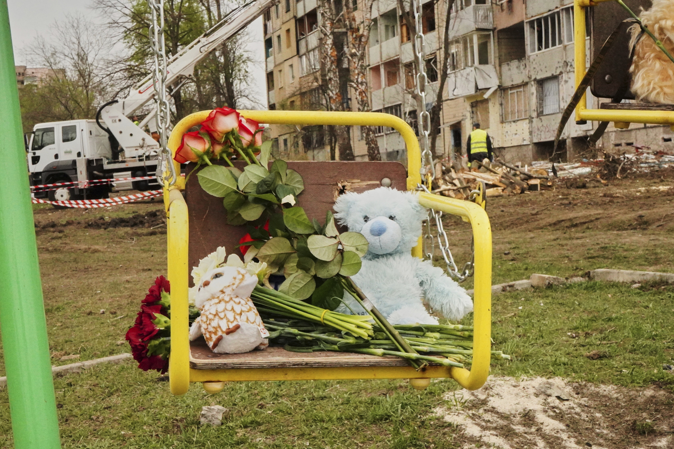 Leksaker och blommor har lämnats på en gunga för att hedra offren på platsen för fredagens ryska attack i Kryvyj Rih i Ukraina. Foto: AP/TT