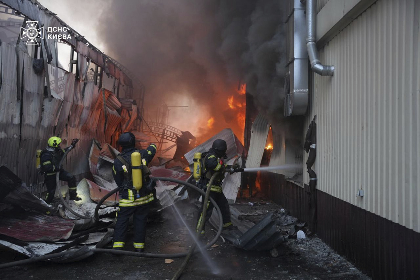 Räddningsarbetare släcker en brand som uppstått till följd av en rysk robotattack mot Kiev under söndagen. Foto: Ukrainas räddningstjänst via AP/TT