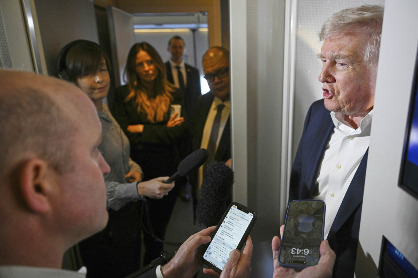 President Donald Trump talar med reportrar ombord på presidentflyget Air force one. Foto: Pool via AP/TT