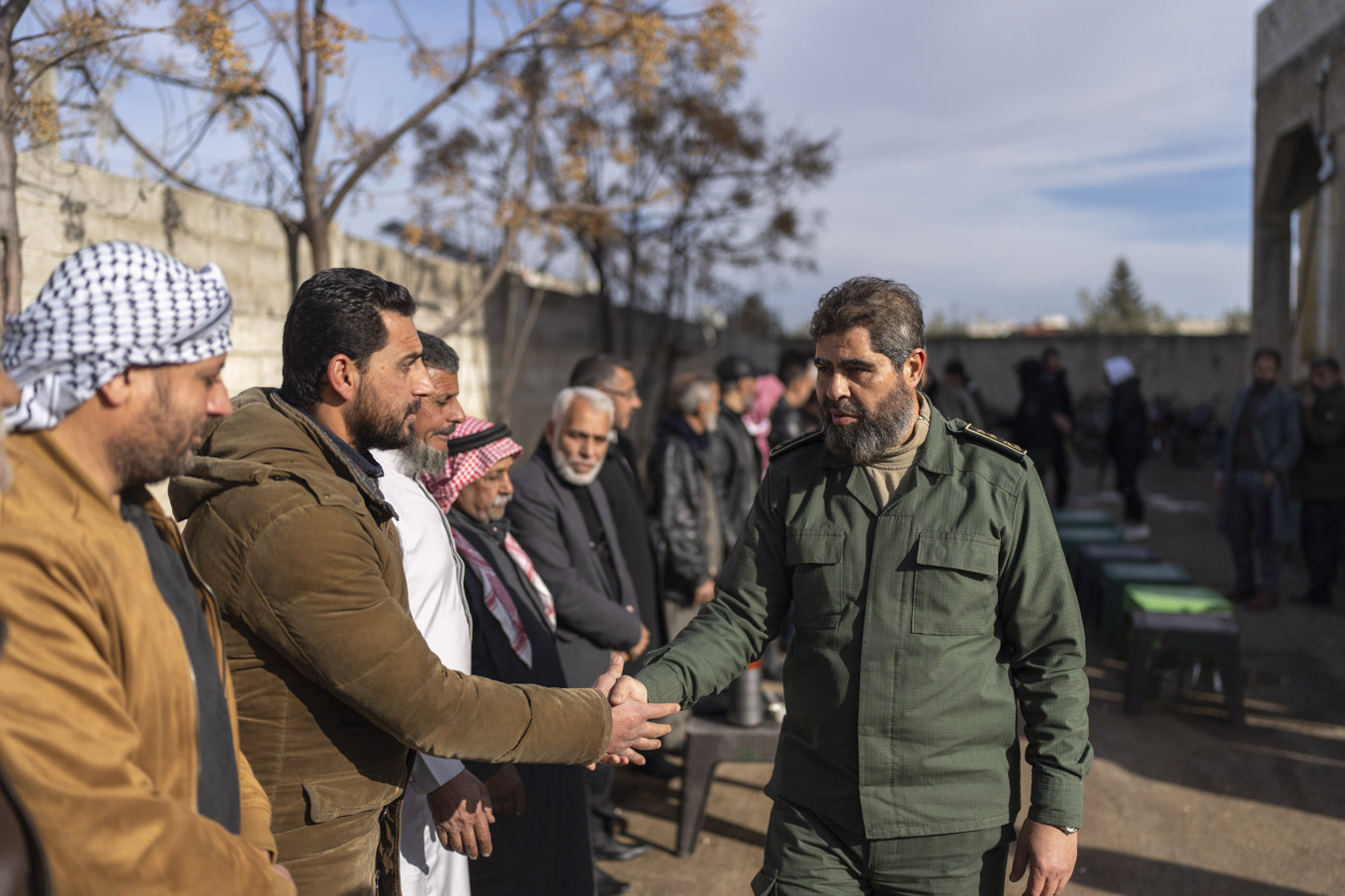 Rebelledaren Ahmed al-Awdeh (höger) skakar hand med lokala tjänstemän i Nawa, drygt tre mil norr om Daraa i södra Syrien. Bild från 4 januari 2025. Foto: Mosa'ab Elshamy/AP/TT