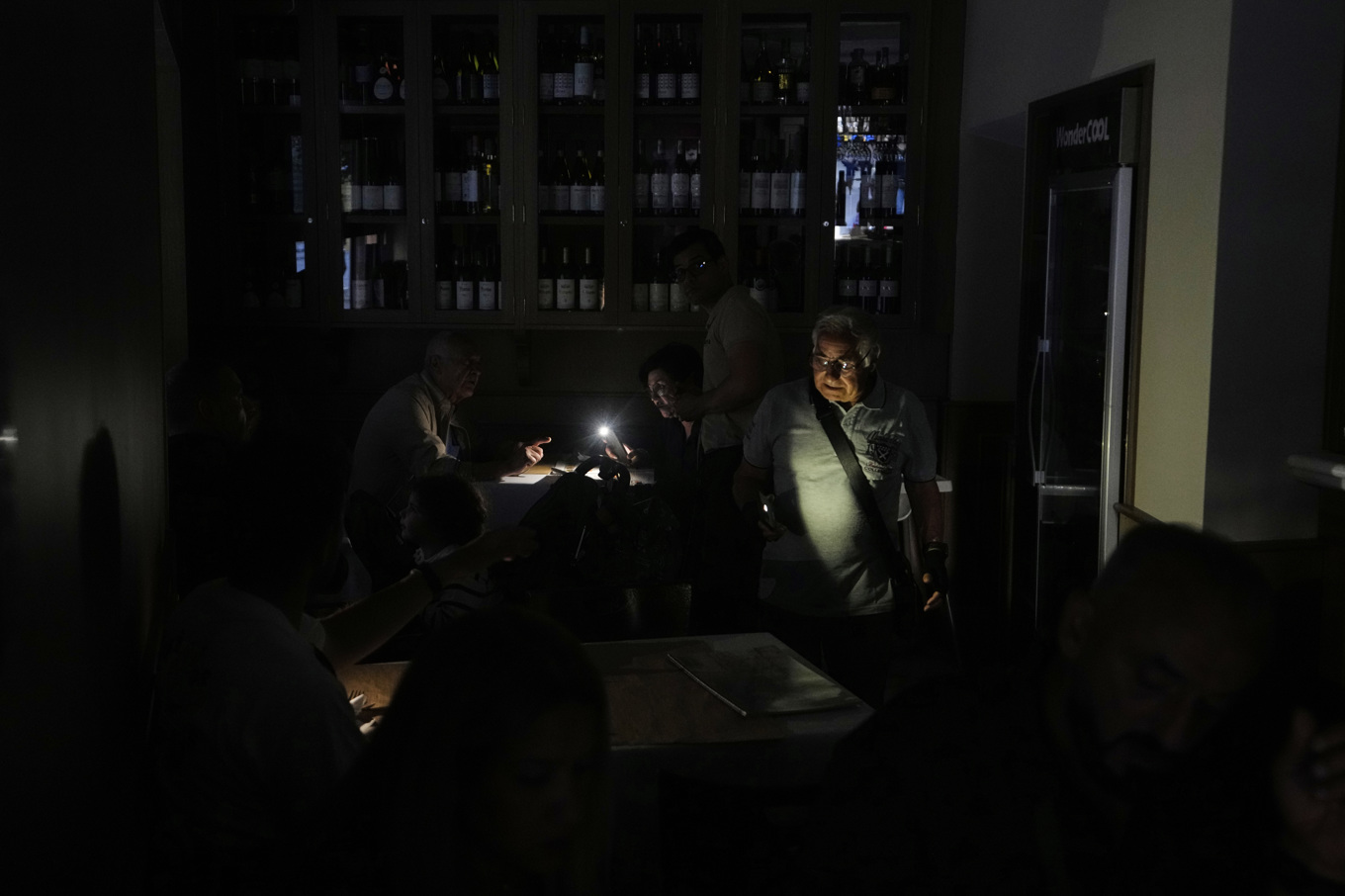 Några personer försöker äta middag i en nedsläckt restaurang i Madrid. Foto: Manu Fernandez/AP/TT