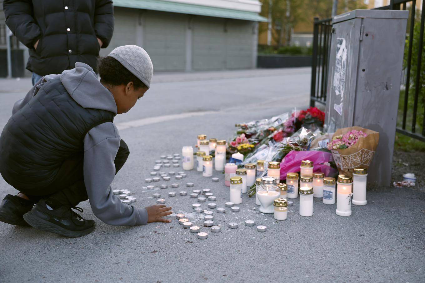 En minnesplats där människor lämnat blommor och ljus dagen efter att tre personer dödats i en skottlossning i en frisörsalong i Uppsala. Foto: Fredrik Persson/TT