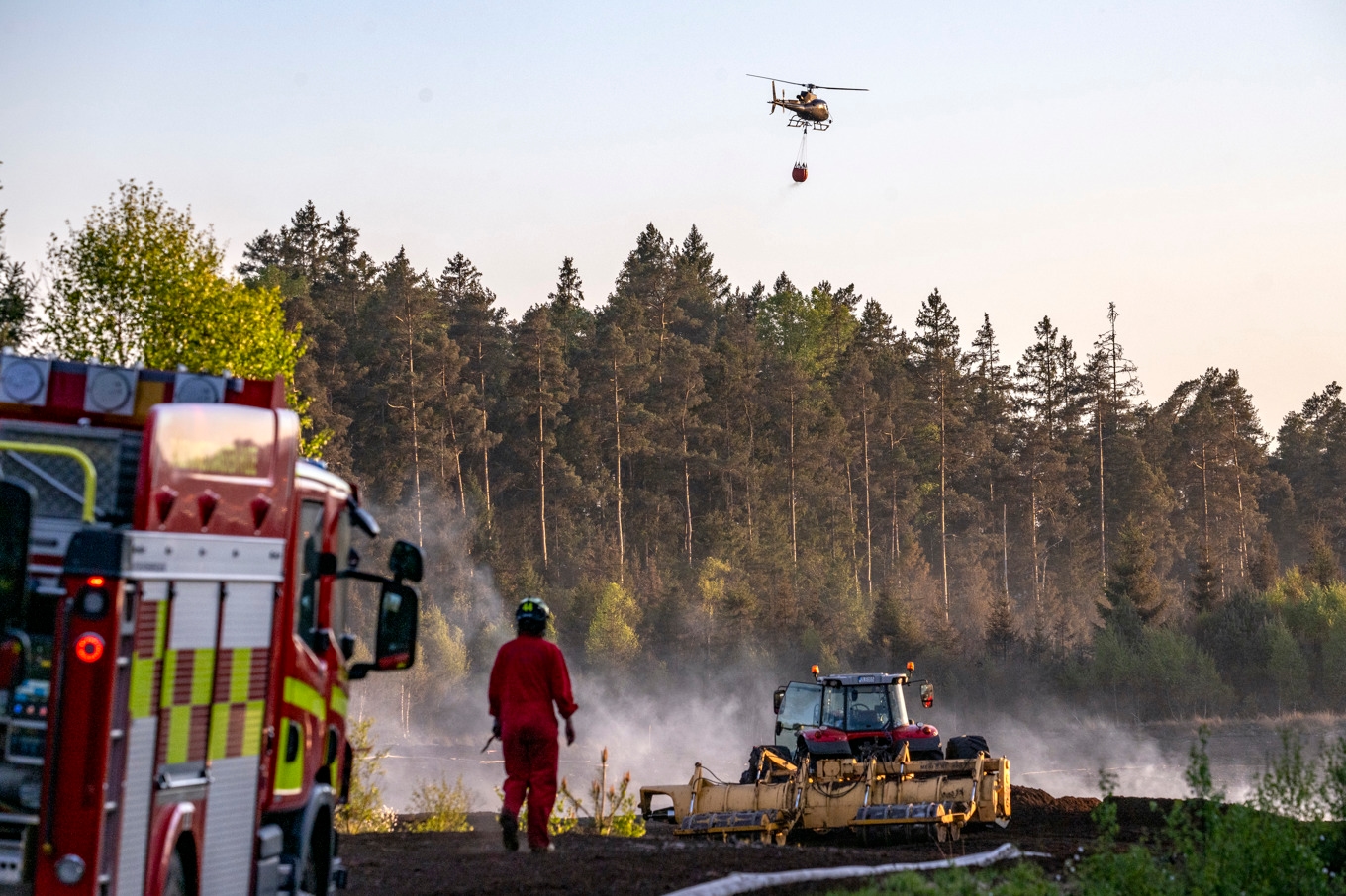Helikoptrar vattenbombar skogen kring en torvtäkt i Kråkeryd utanför Hyltebruk på fredagskvällen. Foto: Johan Nilsson / TT
