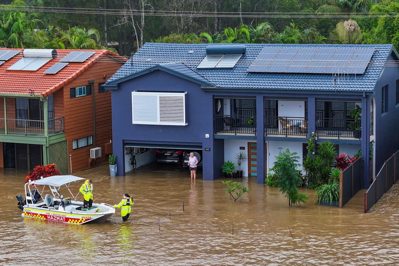 Räddningspersonal bistår en person som strandsatts i sin översvämmade bostad i Port Maquarie i delstaten New South Wales i Australien på torsdagen. Foto: Lindsay Moller/AAP via AP/TT