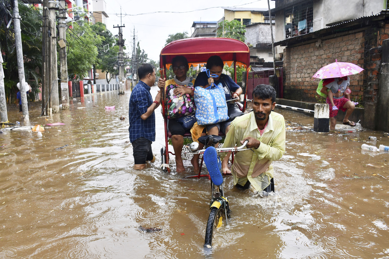 Invånare i staden Guwahati i Assam försöker ta sig över en översvämmad gata. Foto: AP/TT