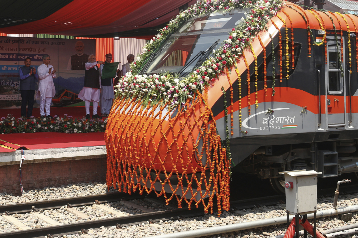 Tåget Vande Bharat Express i Srinagar i Indienkontrollerade Kashmir på fredagen. Premiärminister Narendra Modi står på plattformen med en flagga i handen. Foto: AP/TT