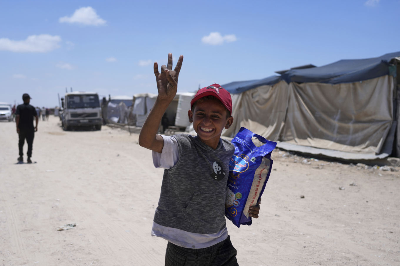En pojke ler efter att ha fått en säck ris från israelisk-amerikanska GHF, som kontrollerar nödhjälpsutdelningen i Gaza. Bild tagen i Khan Yunis i slutet av maj. Foto: Abd al-Karim Hana/AP/TT