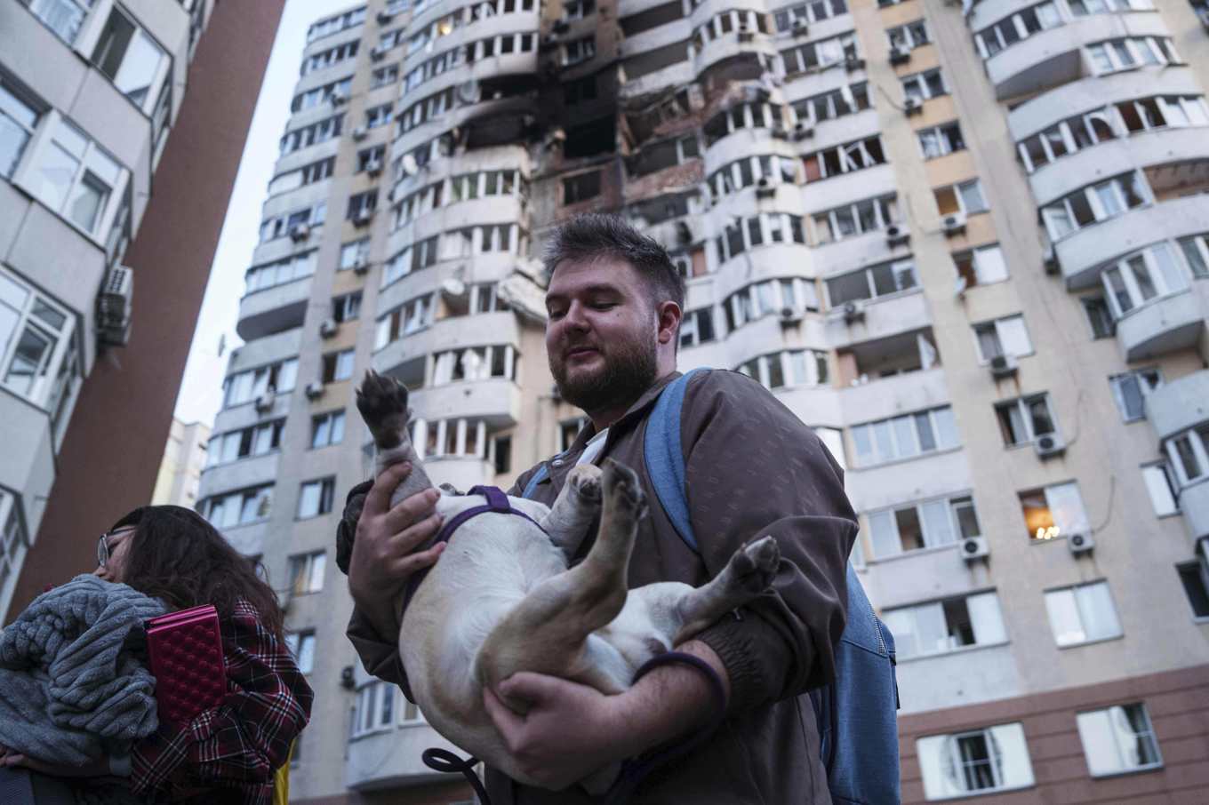En man och hans hund flyr från ett skadat flervåningshus i Kiev på fredagen. Foto: Evgeniy Maloletka/AP/TT