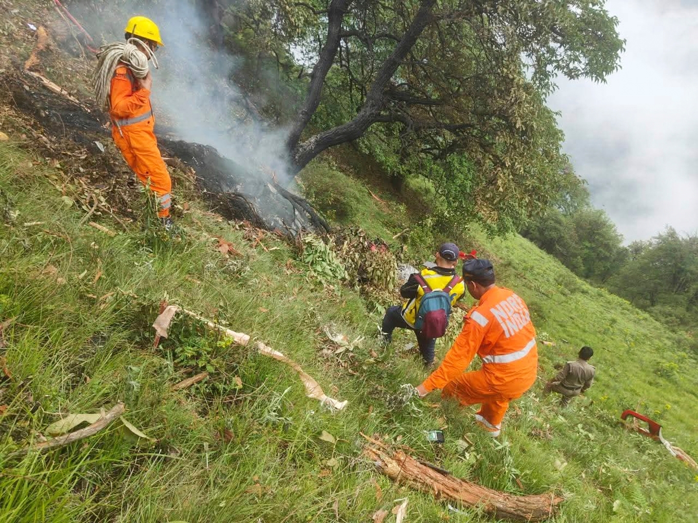 Räddningsarbetare vid platsen där helikoptern kraschade tidigt på söndagen. Foto: Polisen i Uttarakhand via AP/TT
