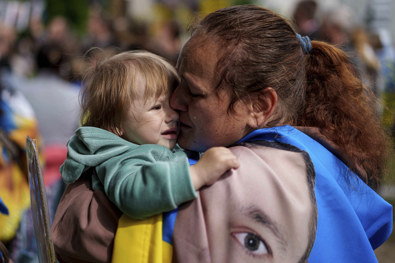 En ukrainsk kvinna, hållande sin dotter samt en skylt på en saknad make och far, i samband med att ukrainska krigsfångar återvände hem i helgen. Fortsatt saknas ett stort antal ukrainska soldater. Foto: Evgeniy Maloletka/AP/TT