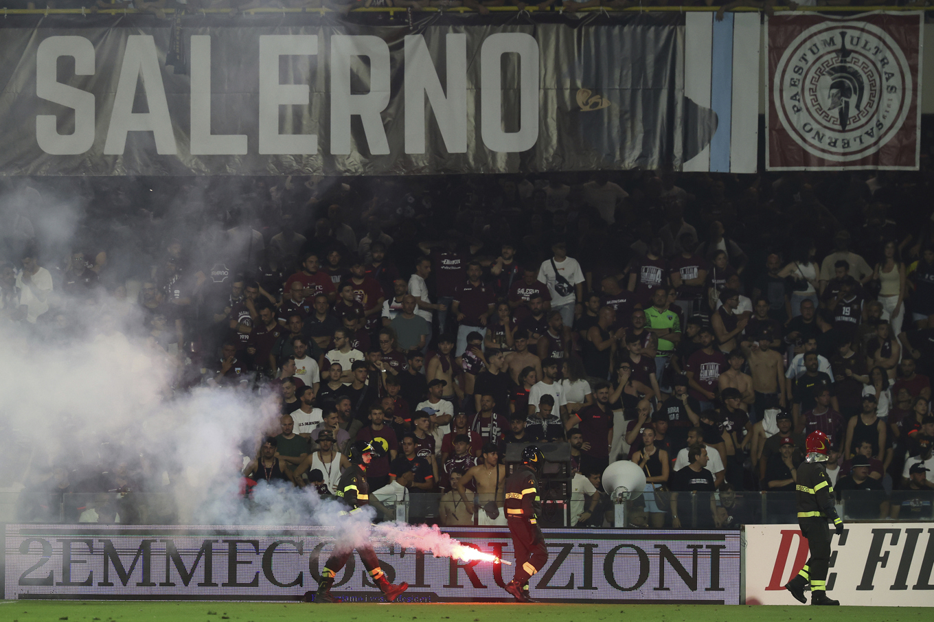 Brandmän hanterar inkastad pyroteknik under matchen mellan Salernitana och Sampdoria. Foto: Alessandro Garofalo/AP/TT
