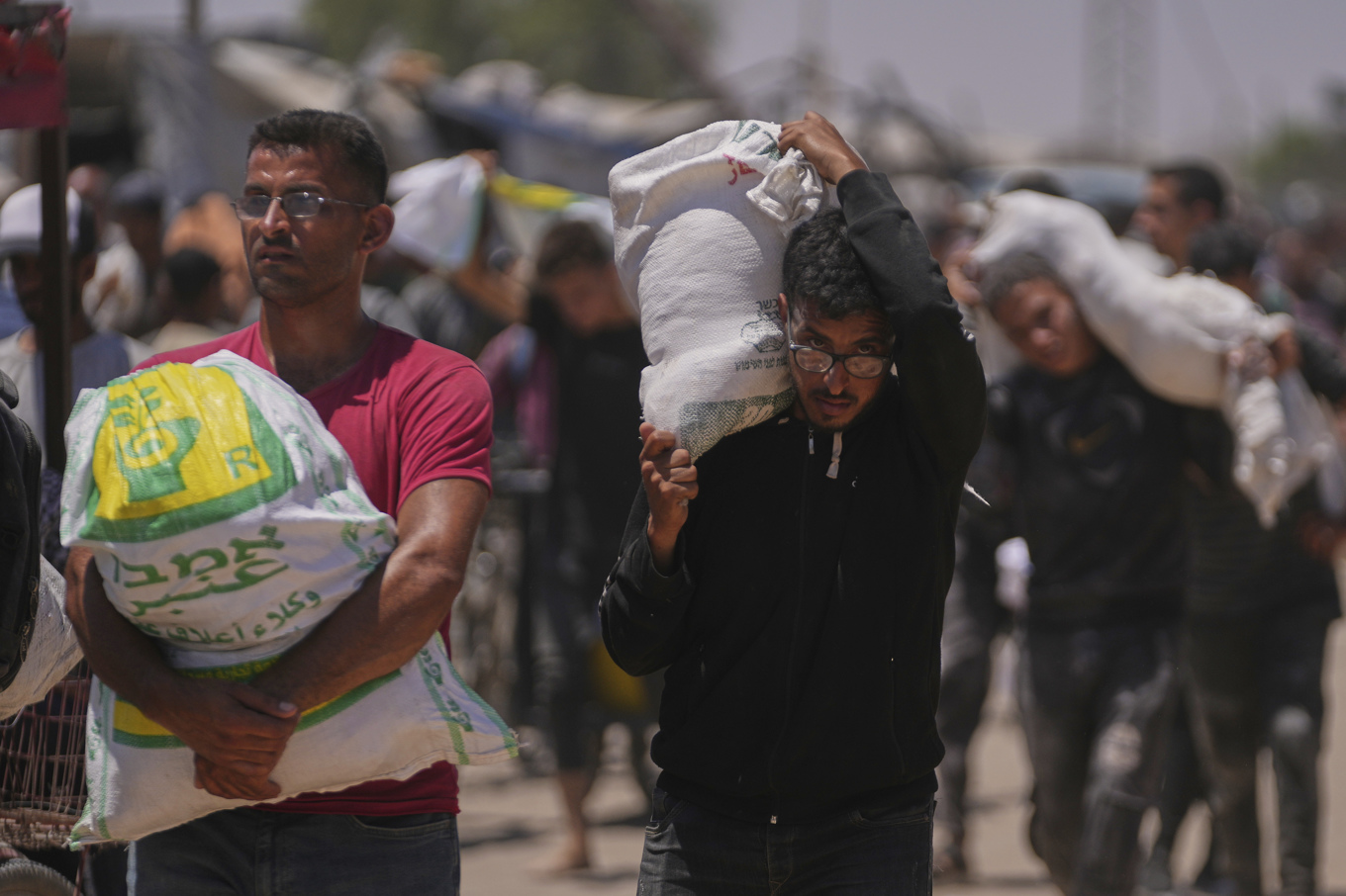 Palestinier bär mat och annan humanitär hjälp som levererats av Gaza Humanitarian Foundation (GHF), i Rafah i södra Gaza tidigare i veckan. Foto: Abdel Kareem Hana/AP/TT
